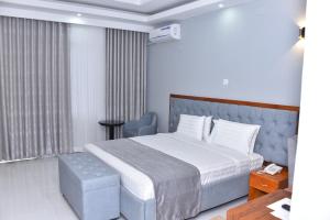 een hotelkamer met een bed, een stoel en een tafel bij KING'S CONFERENCE CENTRE in Bujumbura