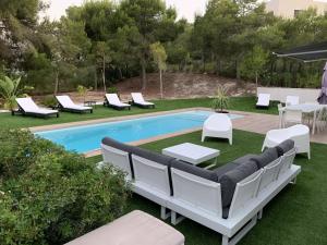 einen Hinterhof mit einem Pool mit Liegestühlen und einem Tisch in der Unterkunft Villa Acacia in Orihuela