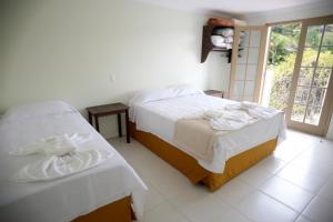 a bedroom with two beds and a window at Residencial Mb in Conservatória