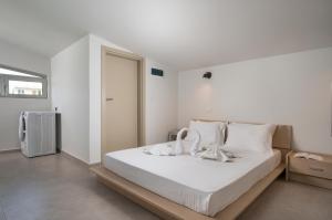 Villa Jarko في مدينة خانيا: غرفة نوم بسرير وملاءات بيضاء وثلاجة