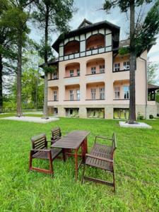 a table and two benches in front of a building at Villa Elizabeth in Kudowa-Zdrój