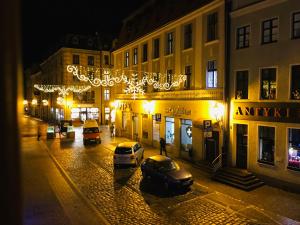 トルンにあるMilky Way Szczytnaの建物前に車を停めた夜の街路