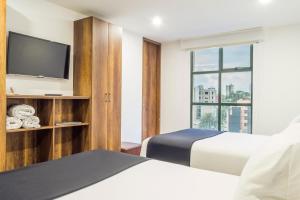 a hotel room with two beds and a flat screen tv at Hotel Black Usaquen in Bogotá