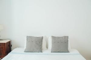 a bed with two pillows and a white wall at Xicotina in Moledo