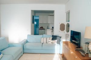 a living room with a blue couch and a television at Xicotina in Moledo