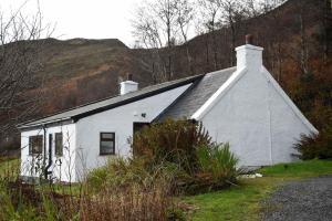 ein weißes Haus mit einem Hügel im Hintergrund in der Unterkunft Bramble Cottage in Ollach