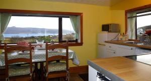a kitchen with a table with chairs and a window at Bramble Cottage in Ollach