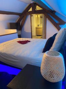 a bedroom with a white bed with a table at Agréable maisonnette de ville avec jacuzzi in Béthisy-Saint-Martin