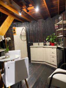 cocina con armarios blancos, mesa y fregadero en Villa Vinicolla Hospedagem Conceito, en Bento Gonçalves