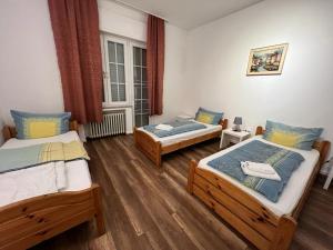 two beds in a room with wooden floors at Pension-Sendis in Herne
