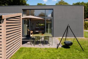 a house with a patio and a table with chairs at Suitelodges Gooilanden in Loosdrecht