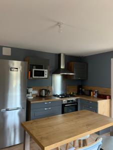 a kitchen with a wooden table and a stainless steel refrigerator at Les métayers du Filou 2 in Castelnau-de-Montratier