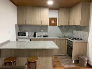 une cuisine avec des placards en bois et un comptoir avec des tabourets dans l'établissement Casa do Julien Mountain Experience, à Vila Real