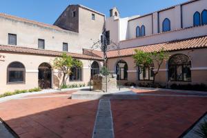 a courtyard of a building with a clock tower at Monastero Santa Chiara Guest House in Oristano