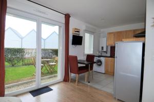 a kitchen with a refrigerator and a table at Jardin - à 50m de la plage - Wifi - Parking in Courseulles-sur-Mer