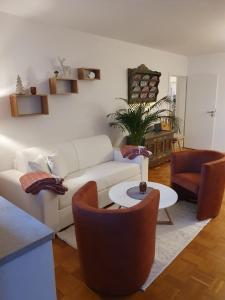 a living room with a white couch and chairs at Ferienwohnung Brünnstein - Alpenmagie Suites in Oberaudorf