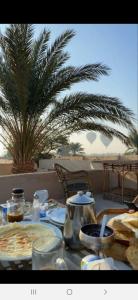 a table with plates of food and a palm tree at Nour El Balad in Luxor