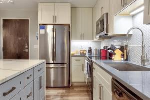 a kitchen with white cabinets and a stainless steel refrigerator at Kasa Forest Park St Louis in Maryland Heights