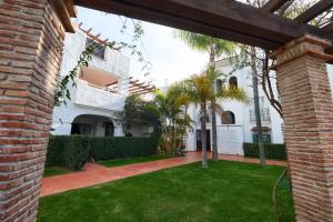 een binnenplaats van een wit huis met een groen gazon bij Beach Side 2 Bedroom apartment in La Gavia San Pedro in Marbella