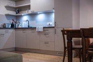 盧茨曼斯堡的住宿－Tschardakenhof Appartements，厨房配有白色橱柜、桌子和椅子