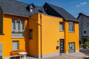 ein gelbes Gebäude mit einer Bank davor in der Unterkunft Schusters Haus in Boppard