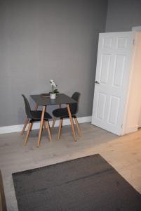 - une table et des chaises dans une pièce avec porte dans l'établissement Kelpies Serviced Apartments- Robertson, à Falkirk