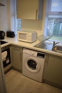 a kitchen with a washing machine and a microwave at Kelpies Serviced Apartments- Robertson in Falkirk