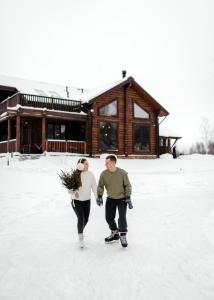 um homem e uma mulher andando na neve em frente a uma cabana em Загородный экопарк и глэмпинг Легенды Леса em Uglich