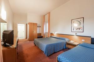 a hotel room with two beds and a television at Hotel Nuova Grosseto in Grosseto