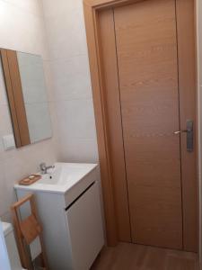 ein Badezimmer mit Waschbecken und Holztür in der Unterkunft Lar Dos Guerreiros in Vila Nova de Milfontes