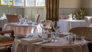 a set of tables with white tablecloths and wine glasses at Colwall Park - Hotel, Bar & Restaurant in Great Malvern
