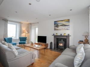 a living room with two couches and a fireplace at Congl Cae in Pwllheli