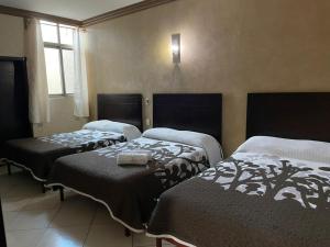 a room with three beds and a window at Hotel San Salvador in San Juan de los Lagos