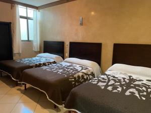 a room with three beds in a room at Hotel San Salvador in San Juan de los Lagos