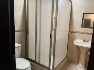 een badkamer met een douche, een toilet en een wastafel bij Hotel San Salvador in San Juan de los Lagos