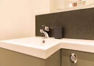 a white sink in a bathroom with a black wall at Greco's Close in Dunbar