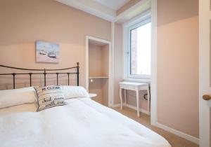 1 dormitorio con cama, ventana y lavamanos en Greco's Close, en Dunbar