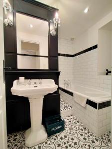 a white bathroom with a sink and a tub at Gîte Eloquent in Gratot