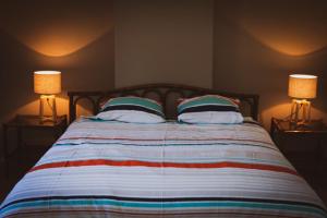 a bedroom with a large bed with two lamps at La petite maison du moulin de Scoville. in Hamois