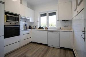 a white kitchen with white appliances and a wooden floor at Casa Mió localizada em pleno centro histórico in Arcos de Valdevez
