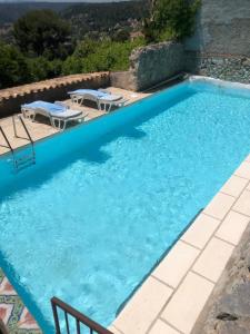 a blue swimming pool with two tables and chairs at La Petite Maison in Saint Paul de Vence
