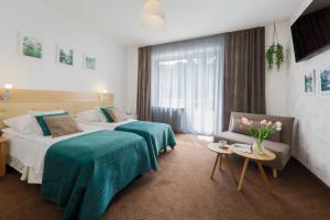 une chambre d'hôtel avec deux lits et une chaise dans l'établissement Hotel Łaziska, à Czchów