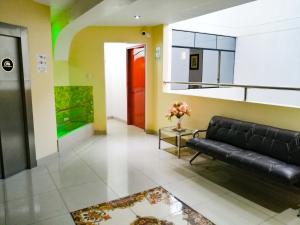 a living room with a black leather couch and a table at Hotel Residencial Los Tres Pinos in Chiclayo