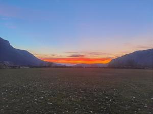 un coucher de soleil sur un champ avec des montagnes en arrière-plan dans l'établissement Konak -Guest house -Ramonda Serbika, à Niš