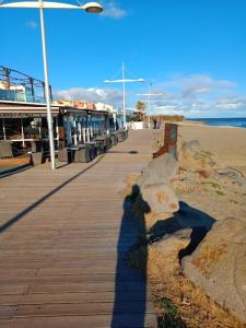 a shadow of a person on a boardwalk near the beach at Studio Cap d'Agde le Môle in Cap d'Agde
