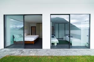 a bedroom with glass doors and a bedroom with a bed at Marvelous Lake Destination eco-friendly villa in Brienno +42 photos