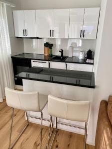 uma cozinha com armários brancos e um balcão preto em Wunderstay Alpine 303 New Studio with Lake & Mountain View em Engelberg