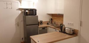 a small kitchen with a refrigerator and a microwave at 2 Appt 4 à 6 pers Val Louron au pied des pistes in Génos