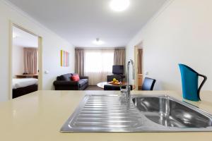 a kitchen with a sink and a living room at Ramada Encore Belconnen in Canberra