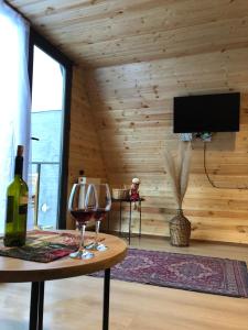 a room with a table with a bottle and a wine glass at Alagi Cottage Kazbegi in Stepantsminda